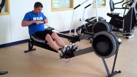 a man in a gym uses a rowing machine